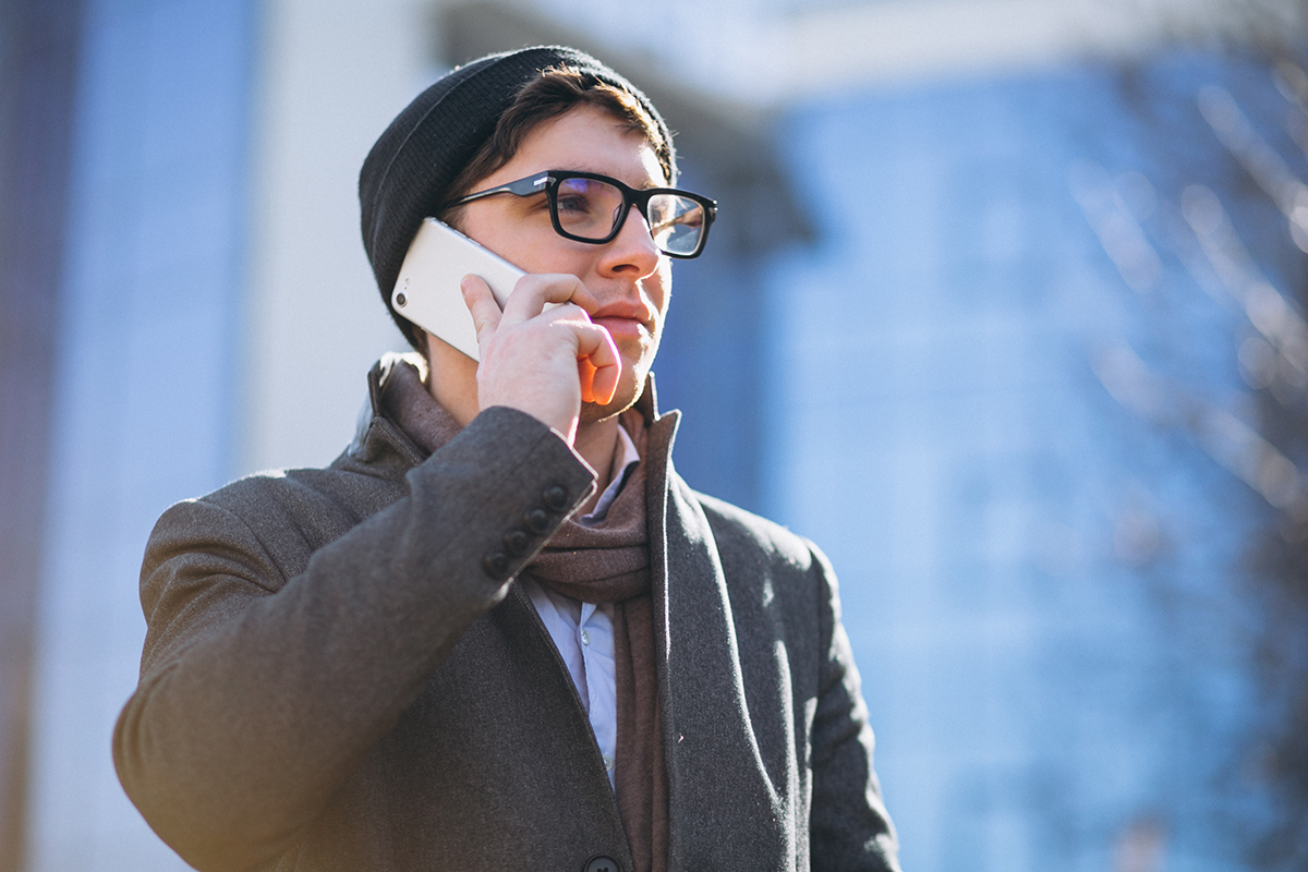 Business man by the skyscraper using phone