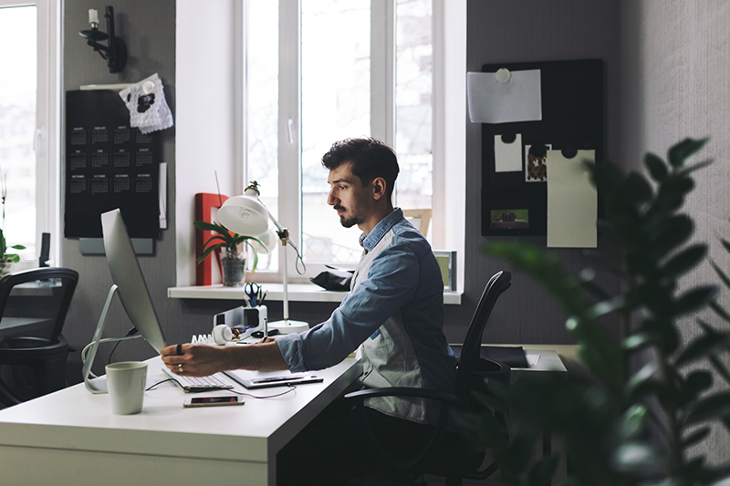 Young man working on computer while sitting at his working place in office