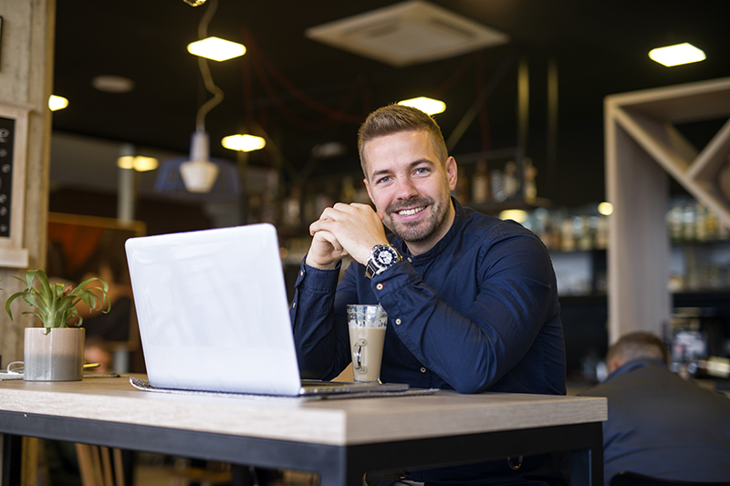 portrait smiling man sitting cafe bar with his laptop computer