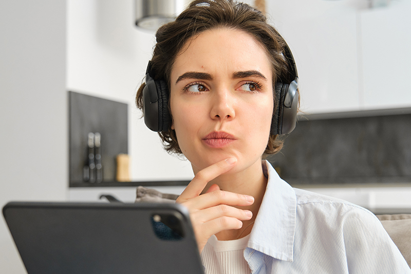 portrait woman studying listening music headphones thinking while working digital tablet